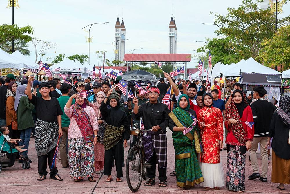Peniaga Haziq Adli Ainuddin, 19, (tengah) bersama peniaga lain ceria memakai busana melayu tradisional dan mengibarkan Jalur Gemilang di sekitar Payang Walk bagi menyemarakkan lagi sambutan Hari Kebangsaan 2023 yang akan disambut 31 Ogos ini.