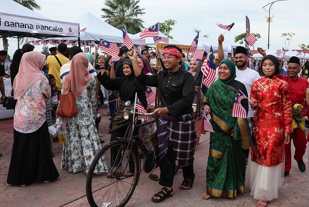 Peniaga Haziq Adli Ainuddin, 19, (tengah) bersama peniaga lain ceria memakai busana melayu tradisional dan mengibarkan Jalur Gemilang di sekitar Payang Walk bagi menyemarakkan lagi sambutan Hari Kebangsaan 2023 yang akan disambut 31 Ogos ini.