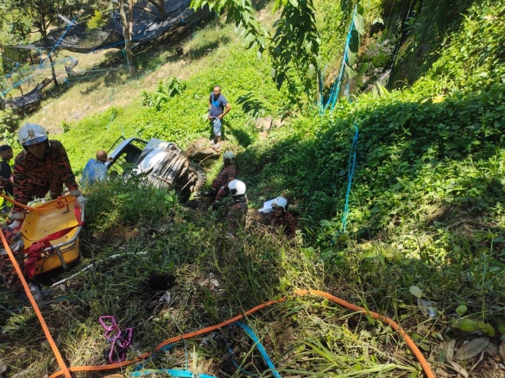Anggota bomba menggunakan tali dan alat pengusung untuk membawa naik mayat mangsa.