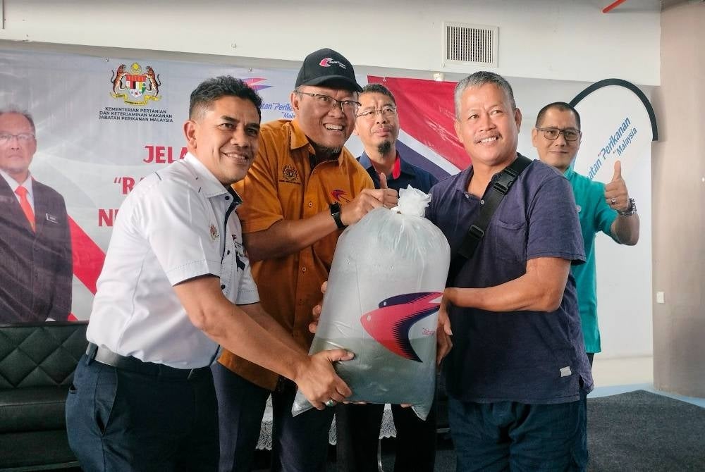 Abdullah (kiri) dan Adnan (tengah) menyerahkan 1,000 ekor benih ikan kepada penternak akuakultur.