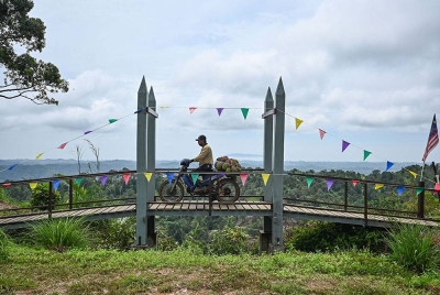 Pekebun Matjed Ismail, 39, melintasi jambatan bermotosikal dengan muatan durian selepas kerja-kerja mengutip buah itu dari kebunnya untuk dijual kepada pelanggan di Kampung Sungai Serai hari ini.