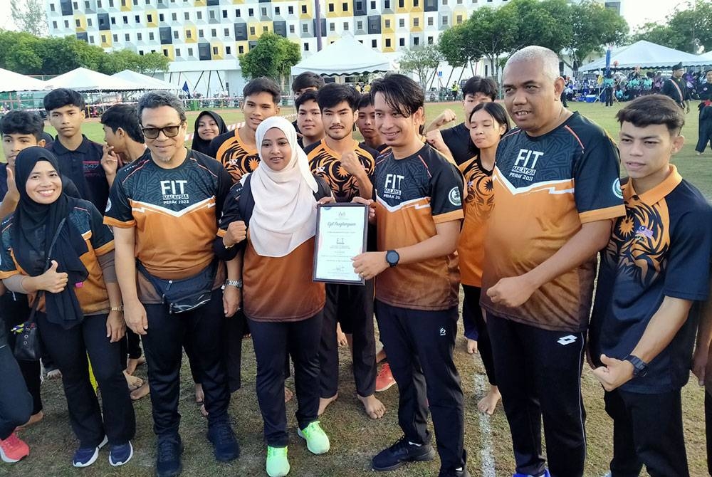 Adam Adli (tiga dari kira) menyampaikan sijil penyertaan kepada atlet-atlet Muaythai sempena Jelajah Fit Malaysia Peringkat Negeri Perak Tahun 2023 di Kompleks Belia dan Sukan Negeri Perak di sini pada Ahad.