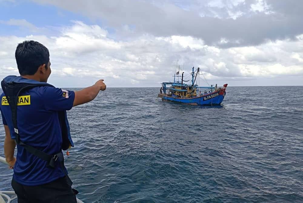 Pegawai Jabatan Perikanan yang menjalankan rondaan menahan sebuah bot pukat tunda di Kepulauan Sembilan, Pulau Pangkor. - Foto: Jabatan Perikanan Perak