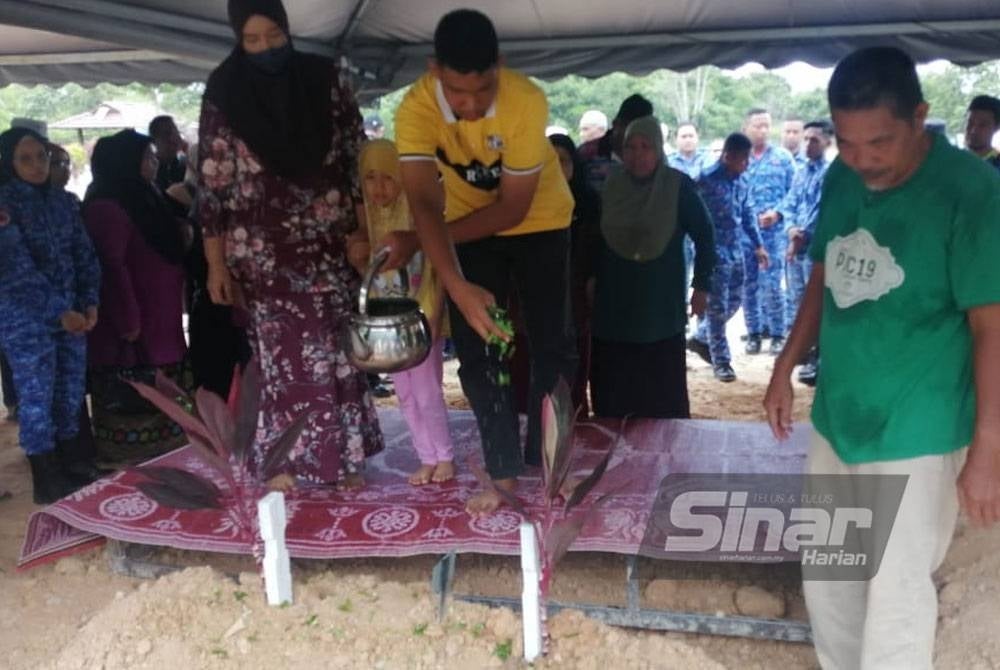 Suriana bersama dua anak menyiram air mawar ke pusara arwah Sharipuddin