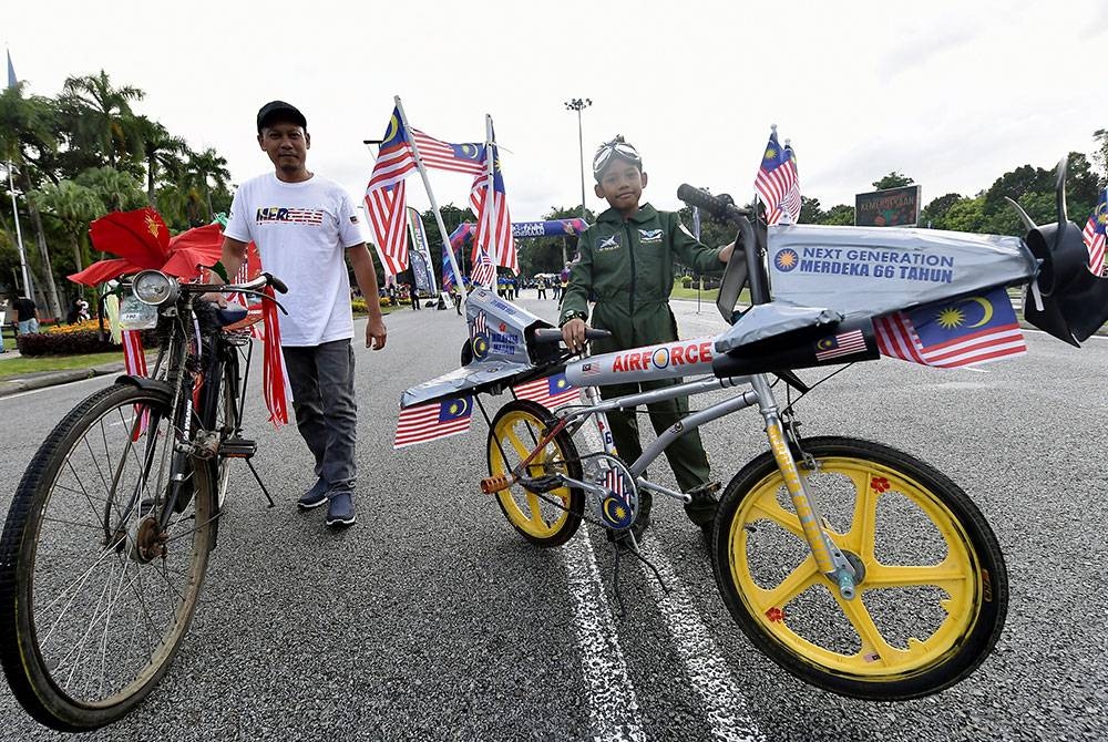 Zulhisam Nasiran, 43, (kiri) bersama anaknya, Rayqal Huzaimi Zulhisam, 10, (kanan) memperagakan basikal masing-masing yang dihiasi dengan Jalur Gemilang sempena menyambut bulan kebangsaan semasa turut serta dalam Program Shah Alam Hari Tanpa Kenderaan dan CEO Run 2023 di Dataran Kemerdekaan Shah Alam hari ini.