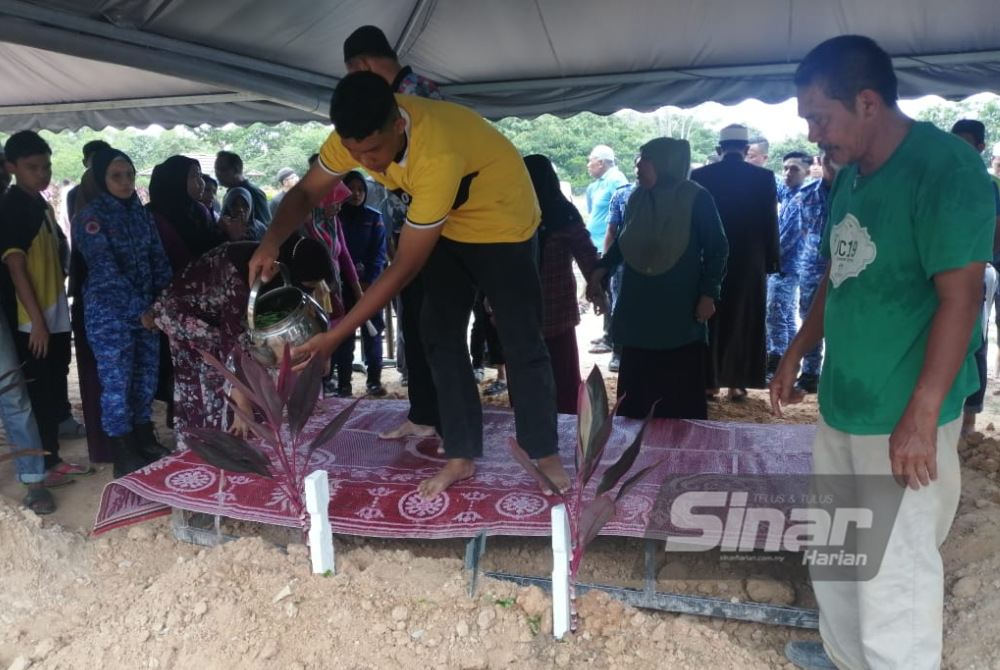 Muhammad Sharul Izuan menyiram air mawar di pusara bapanya. 