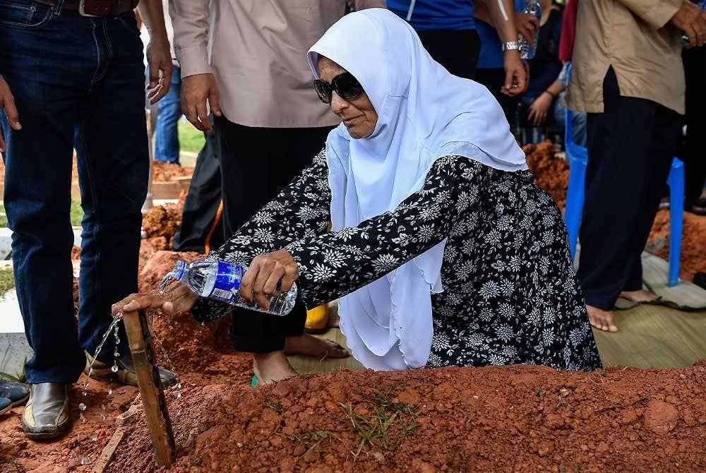 Rohani menyiram air mawar di pusara anaknya, Mohammad Taufiq selepas selesai urusan pengebumian di Tanah Perkuburan Islam Ukay Perdana hari ini. - Foto Bernama