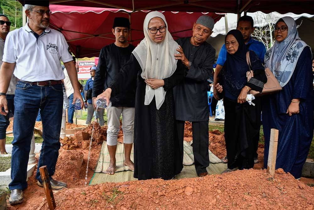 Suzana (tengah) tidak dapat menahan kesedihan ketika menyiram air mawar di pusara suaminya, Mohammad Taufiq selepas selesai urusan pengebumian di Tanah Perkuburan Islam Ukay Perdana hari ini. - Foto Bernama