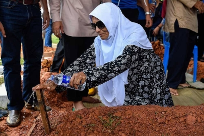 Rohani menyiram air mawar di pusara anaknya, Mohammad Taufiq selepas selesai urusan pengebumian di Tanah Perkuburan Islam Ukay Perdana hari ini. - Foto Bernama