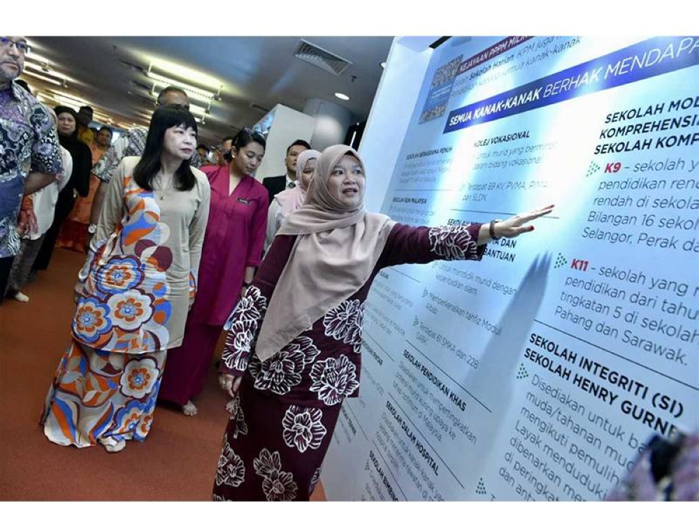 Fadhlina menunjukkan maklumat mengenai pencapaian semasa PPPM sambil diperhatikan Timbalan Menteri Pendidikan, Lim Hui Ying (kiri) ketika majlis pelancaran Laporan Tahunan 2022 PPPM di Perpustakaan Raja Tun Uda, Shah Alam pada Selasa.