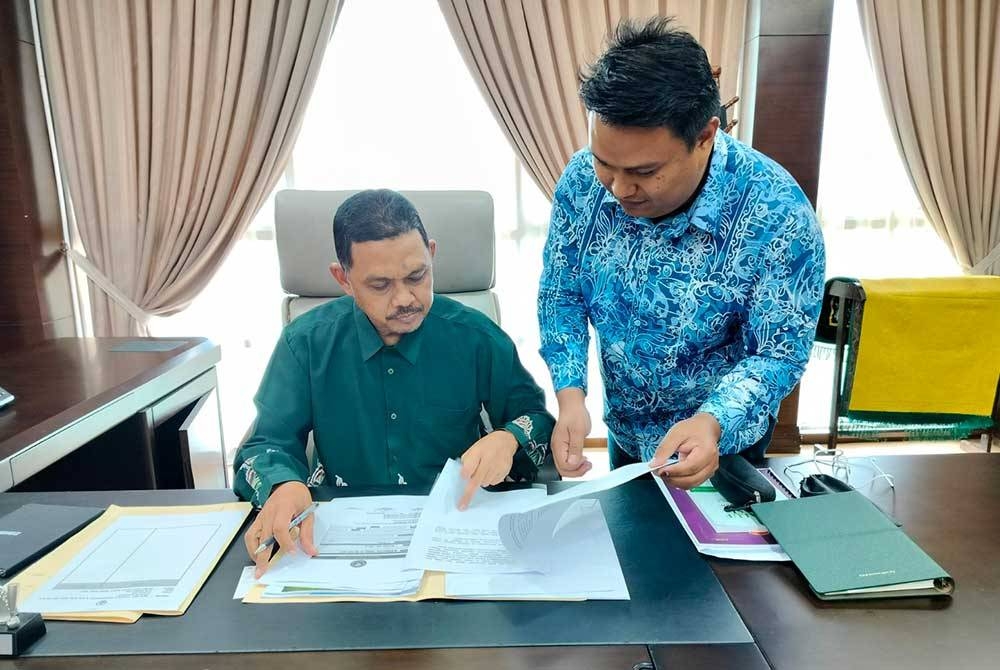 Mohamad Radhi (kiri) dibantu oleh salah seorang pegawainya, Khairuddin Md Isa di pejabatnya di Wisma Darul Aman di sini pada Khamis.