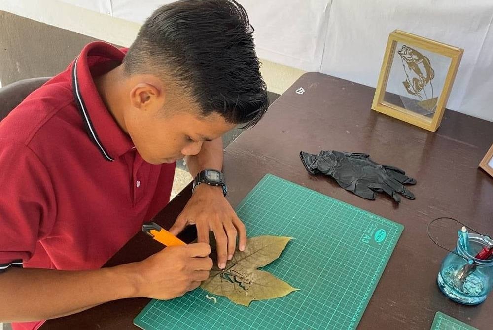 Muhammad Azam menukar daun ke dalam bentuk wang menerusi lukisan potret yang dihasilkan menggunakan bahan terbuang itu.