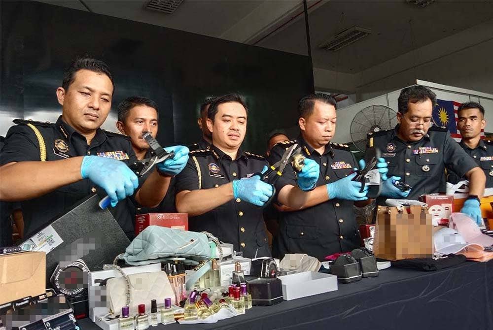 Mohd Zuhairi (tiga darikiri) menggunting barangan dipercayai tiruan.