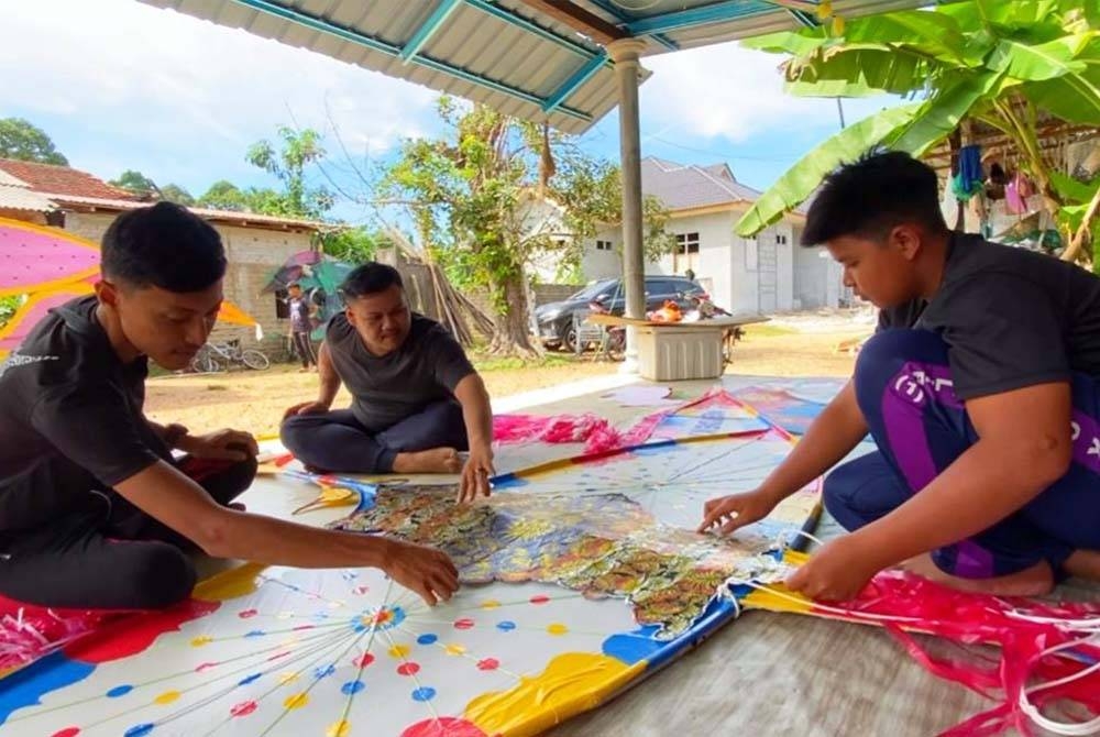 Che Faris (tengah) dibantu awak-awak menyiapkan wau puyuh gergasi sempena kemerdekaan ke-66.