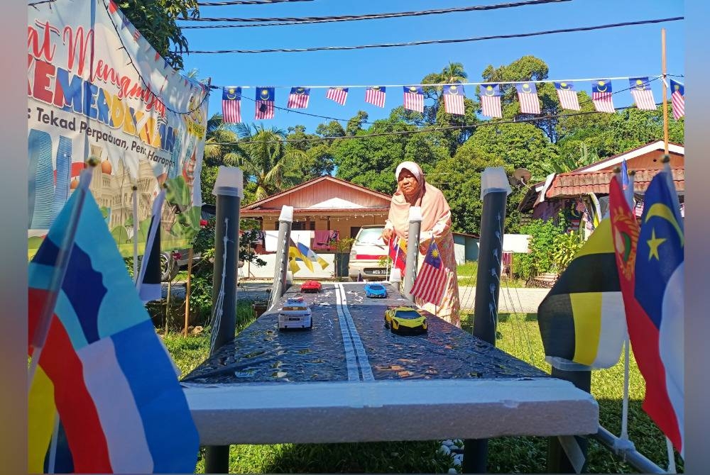 
Fatimah menunjukkan replika Jambatan Pulau Pinang yang dipasang bagi memberi kelainan sempena program Halaman Rumah Merdeka.