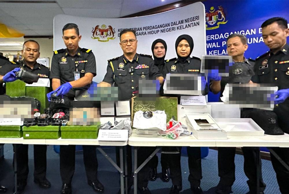 Azman (empat dari kiri) menunjukkan beg-beg tiruan yang dirampas oleh pihaknya.