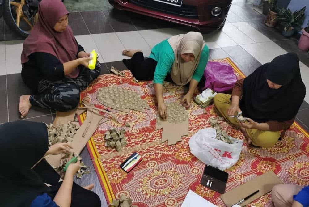 Penduduk bekerjasama menyiapkan hiasan lorong menggunakan bahan terpakai.