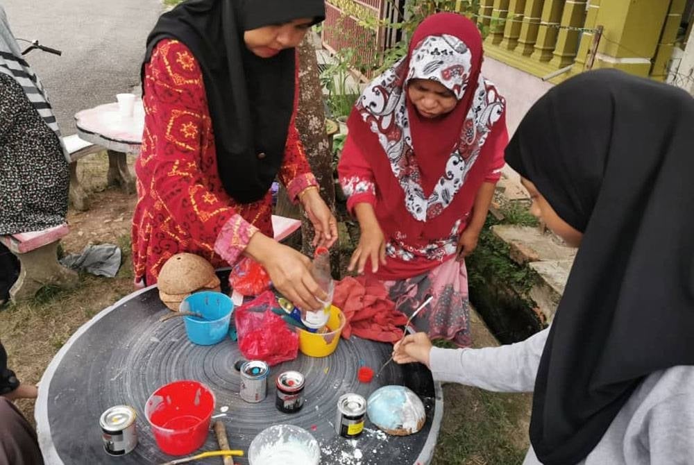 Penduduk bekerjasama menyiapkan hiasan lorong menggunakan bahan terpakai, tempurung kelapa.