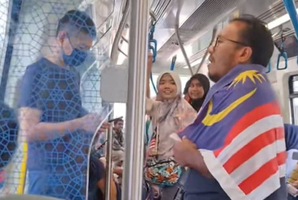 Tangkap layar video TikTok menunjukkan seorang lelaki dengan Jalur Gemilang menyanyikan lagu 'Tanggal 31' sebelum diikuti oleh pengguna MRT yang lain