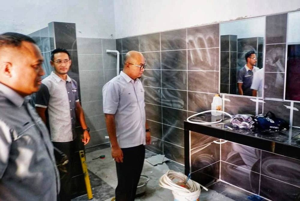 Fadzli (kiri) bersama Izad (tengah) melihat keadaan dalam tandas di SDM.