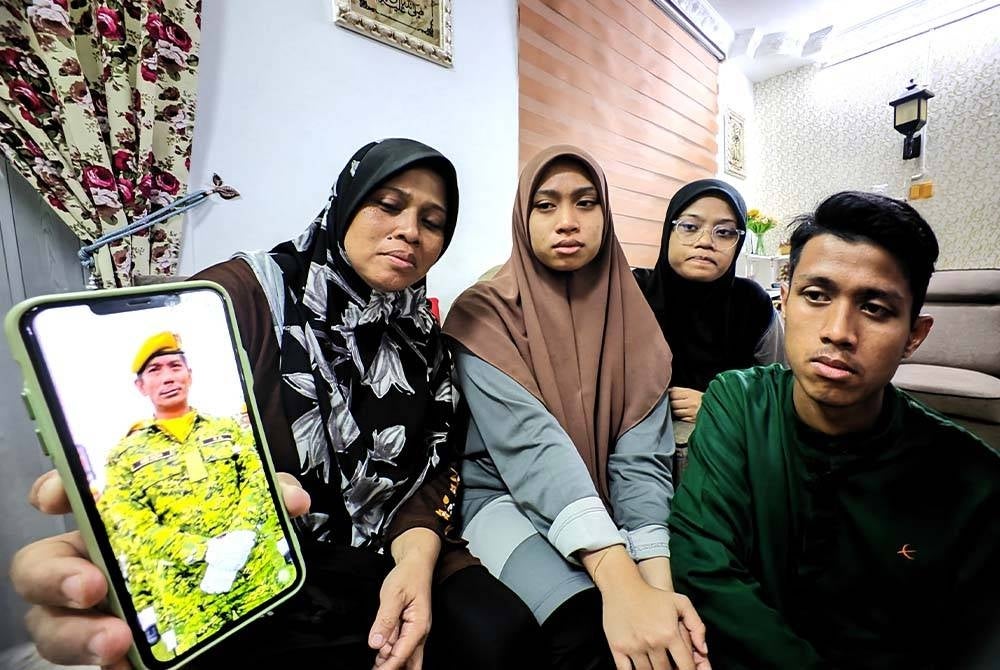 Maniliza (kiri) menunjukkan gambar Allahyarham sambil diperhatikan tiga anaknya.