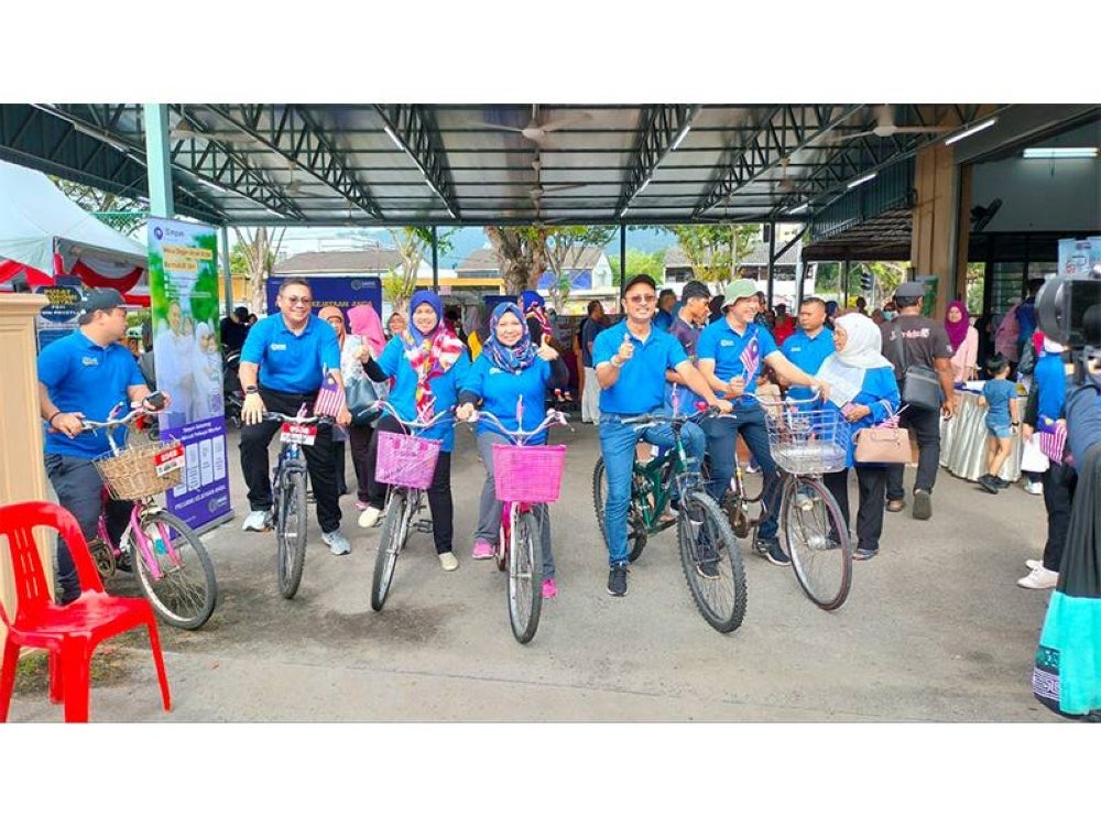 Norliza (empat dari kiri) menyertai Kayuhan Semarak Kasih Merdeka PTPTN 2023 iaitu aktiviti kayuhan basikal secara berkumpulan sambil mengibarkan bendera Malaysia dan agihan sumbangan bakul makanan dari rumah ke rumah.