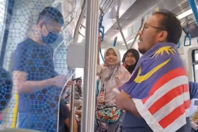 Tangkap layar video TikTok menunjukkan seorang lelaki dengan Jalur Gemilang menyanyikan lagu 'Tanggal 31' sebelum diikuti oleh pengguna MRT yang lain