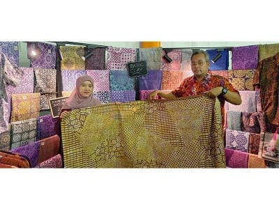 Mohamad Rizan (kanan) menunjukkan batik tanah liat yang diusahakan oleh Nur Nabihah Zakaria sempena Festival Kraf Perak 2023 di Dataran Menara Condong, Teluk Intan, Perak.  
