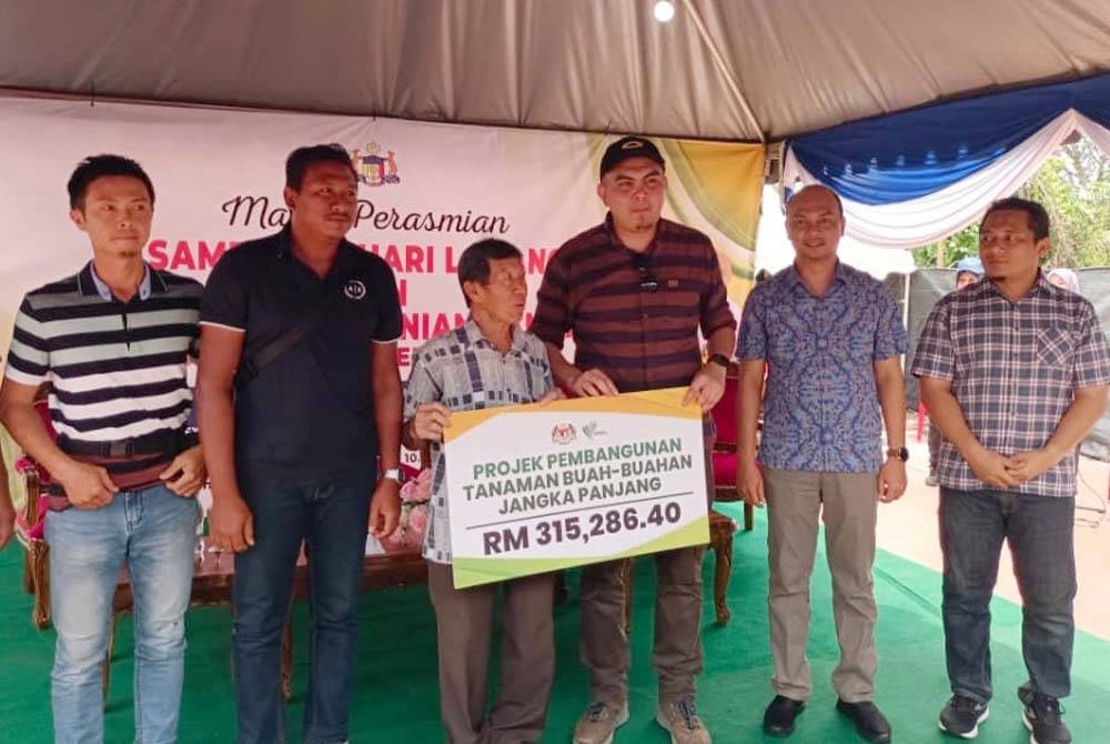 Dr Muhamad Akmal (empat dari kiri) dan Fairulnizam (lima dari kiri) ketika menyampaikan replika cek kepada penerima bantuan pertanian ketika program Hari Ladang Peringkat Daerah Jasin 2023 di Selandar, pada Sabtu.