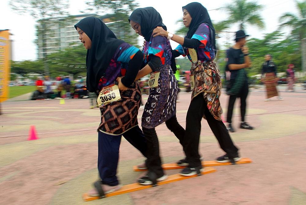 Bersemangat para peserta Sukan Rakyat Sarong bersaing dalam acara terompah gergasi pada program Sarong Festival di Bulatan Sultan Azlan Shah hari ini.
