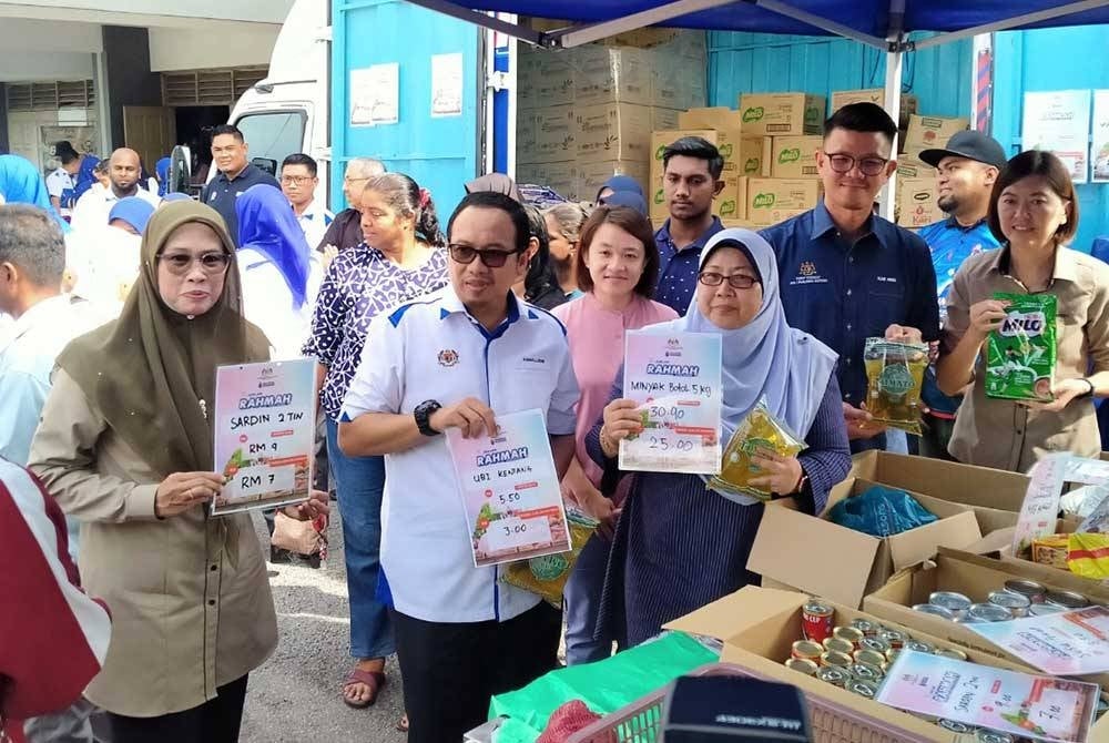 Fuziah (tengah) menunjukkan antara barangan yang dijual sempena Program Jualan Rahmah Bergerak Peringkat Negeri Perak di Dewan Bandaran Gopeng pada Ahad.