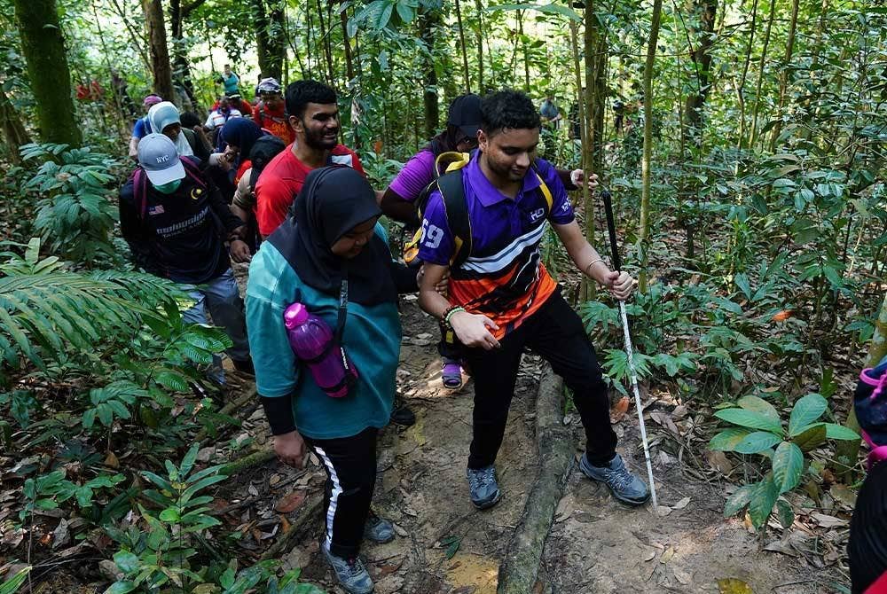 Peserta OKU dibantu untuk mendaki Bukit Kerinchi. - FOTO :MOHD HALIM ABDUL WAHID
