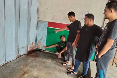 Zahid (duduk, kiri) menunjukkan kesan darah di lokasi kejadian.