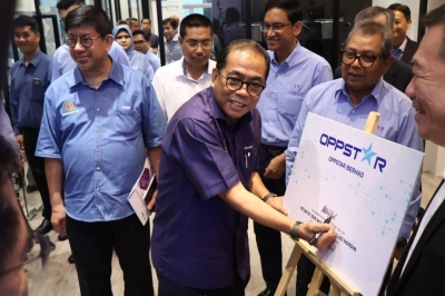 Mohamed Khaled menandatangani plak ketika mengadakan lawatan ke Oppstar Technology Sdn Bhd di Bangunan 12U, Sains@USM di Bukit Jambul pada Isnin.
