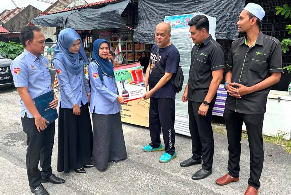 Nora (dua dari kiri) dan Abdullah (tiga dari kiri) melihat kaki palsu yang diberikan kepada Kamarudin (tengah).