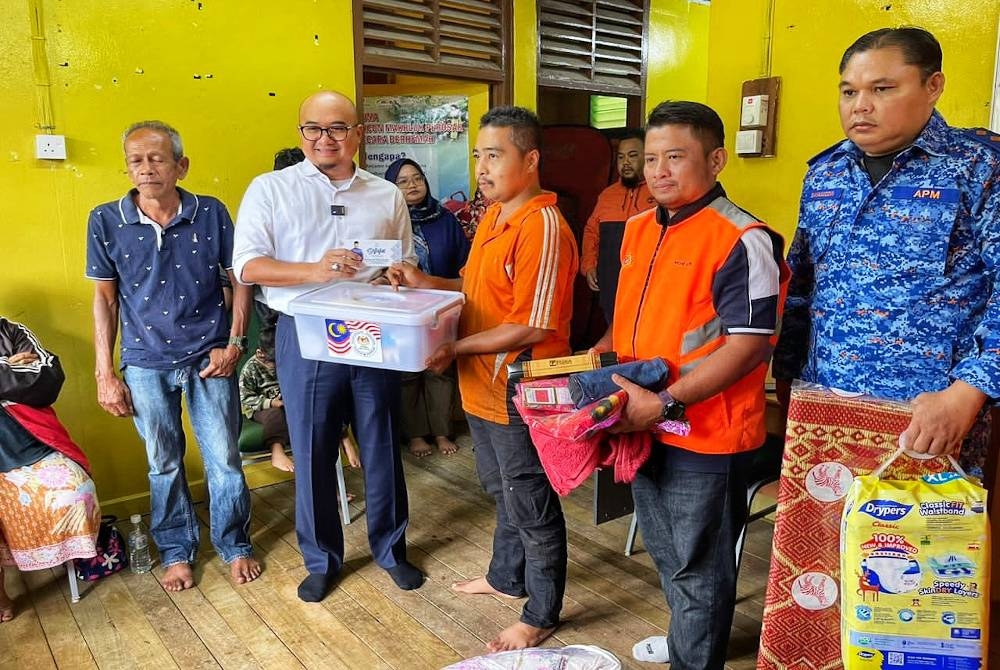 Fadzli (dua dari kiri) menyerahkan sumbangan kerajaan negeri kepada mangsa banjir kilat di Raub.