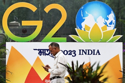 Pejalan kali melepasi logo G20 yang dipasang di jalan raya di New Delhi, India. - Foto AFP