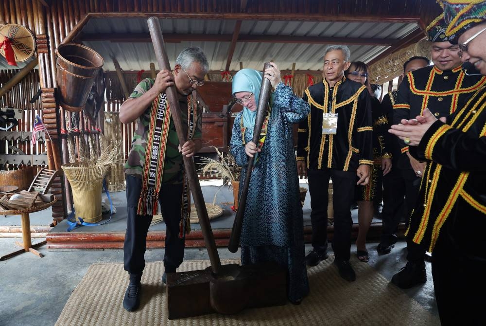 Al-Sultan Abdullah dan Tunku Azizah berkenan mencuba peralatan tradisional menumbuk padi ketika melawat ke Kompleks Persatuan Kebudayaan Kadazandusun (KDCA). - Foto Bernama