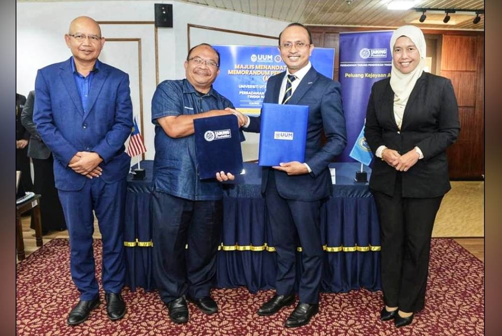 Mohd Foad (dua dari kiri) dan Ahmad Dasuki bertukar-tukar dokumen pada Majlis Menandatangani MoU antara UUM dan PTPTN di Balai Tamu, UUM.