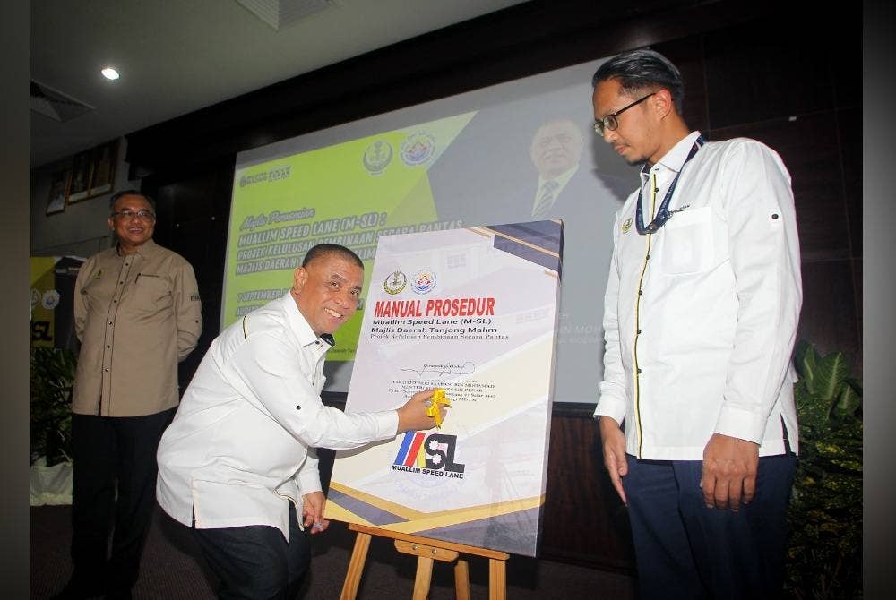 Saarani menandatangani plak simbolik merasmikan M-SL: Projek Kelulusan Pembinaan Secara Pantas sambil diperhatikan Yang Dipertua MDTM, Mohd Ikram Ahmad (kanan).