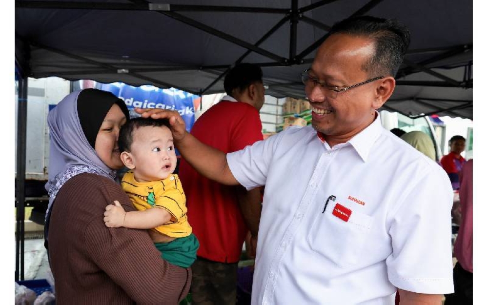 Suhaizan beramah mesra dengan seorang kanak-kanak ketika mengadakan walkabout menemui para pengundi di kawasan Parlimen Pulai pada Rabu. FOTO: BERNAMA