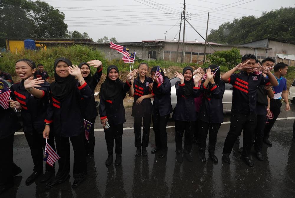 Orang ramai sanggup dibasahi hujan kerana terlalu ingin bertemu dengan Al-Sultan Abdullah dan Tunku Azizah. - Foto Bernama