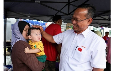 Suhaizan beramah mesra dengan seorang kanak-kanak ketika mengadakan walkabout menemui para pengundi di kawasan Parlimen Pulai pada Rabu. FOTO: BERNAMA