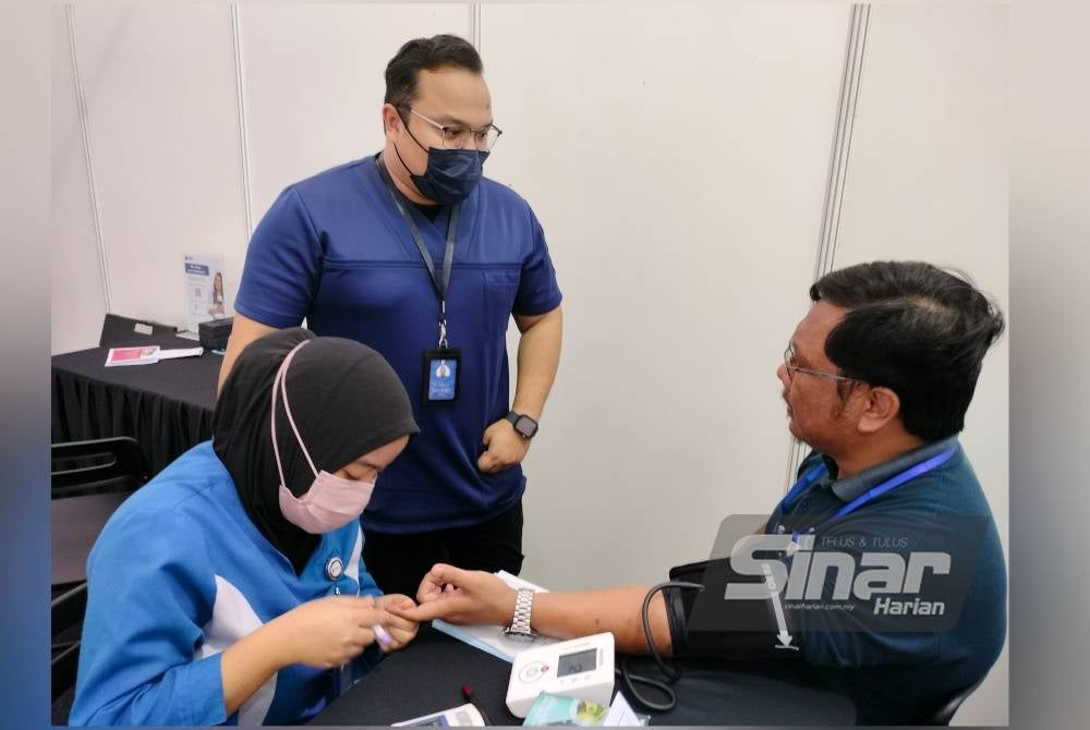 Dr Zulkarnain (tengah) menyantuni pengunjung yang hadir ke reruai Pantai Hospital Ampang.
