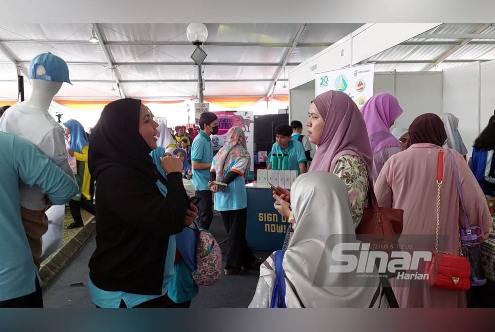 Azura (kiri) sedang berbual dengan salah seorang pengunjung di Karnival Pendidikan Sinar Bestari pada Jumaat