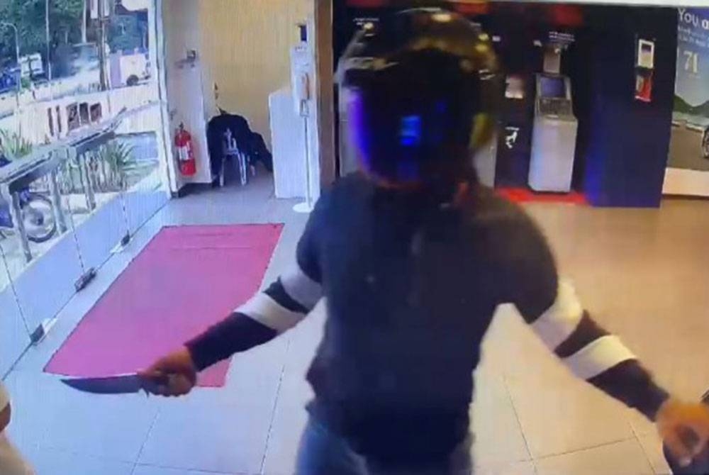 Tangkap layar menunjukkan seorang lelaki bersenjatakan pisau melakukan samun dan melarikan wang milik mangsa di sebuah bank di Ipoh. - Foto: Ihsan Pembaca