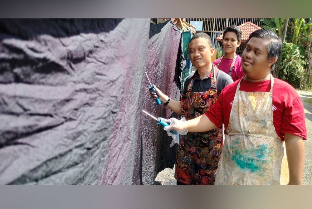Dari kanan Mohammad Nazif Mohd Ali dan Mohammad Luqman yang berdepan masalah pembelajaran bersama tenaga pengajar, Muhammad Fathi Syameer (belakang) melakukan proses menyiapkan batik di PPDK Merbok.