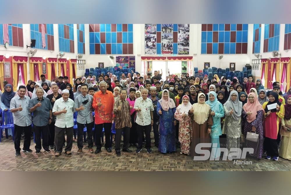 Muhammad Nasir (tengah) merakam gambar bersama penerima sumbangan sempena majlis penyampaian bantuan program SAS kali ke-16 di Dewan Jubli Sekolah Menengah Kebangsaan Tengku Mahmud, Besut pada Sabtu.