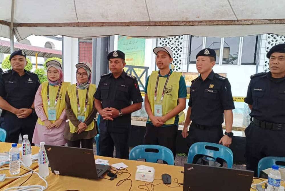 Ayob Khan (tengah) bergambar bersama petugas SPR di pusat mengundi Maktab Sultan Abu Bakar pada Sabtu.
