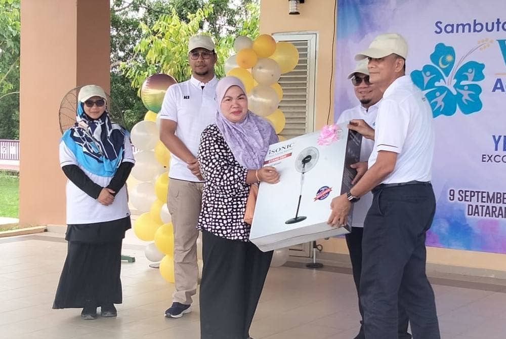 Dr Zaini (kanan) menyampaikan hadiah cabutan bertuah kepada pengunjung program Sambutan Wellness Month Peringkat Negeri Kelantan 2023 pada Sabtu.